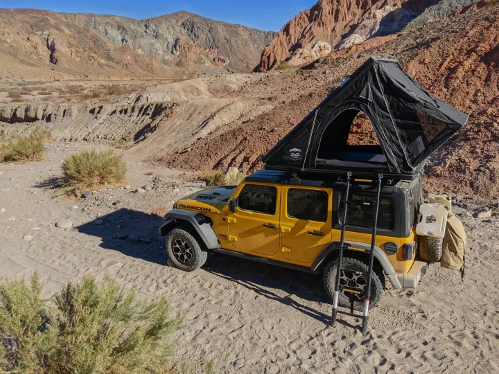 Bright yellow Jeep with deployed roof-top tent, ready for a rugged desert rv rental adventure. Ideal for off-grid camping.. Jeep Wrangler Unlimited Rubicon 2020