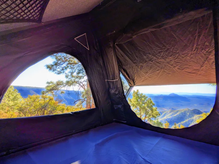 Interior of an RV rental rooftop tent, showcasing expansive mountain views through large arched windows. Ideal for nature lovers.. Jeep Wrangler Unlimited Rubicon 2020