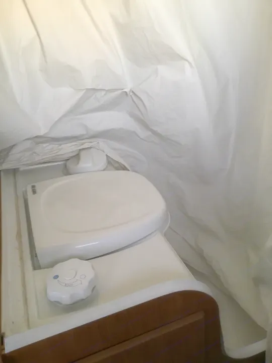RV rental: Inside, a white pop-up wall meets a compact RV toilet featuring an "OPEN" dial for operation.. Coleman Fairlake 2002