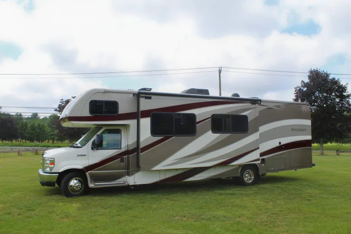 Spacious Class C rv rental parked on a green grassy field under a cloudy sky, ready for outdoor adventures.. Forest River Sunseeker 2018