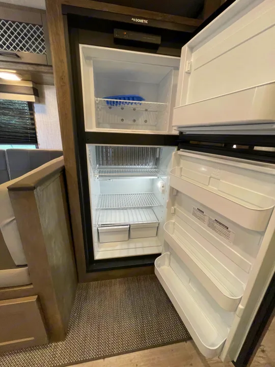 Inside an open Dometic RV refrigerator & freezer, with shelves and bins visible. Perfect for your next RV rental.. Heartland North Trail 2021