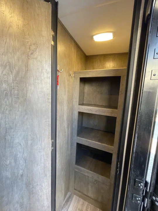 Inside an RV rental: view of handy storage shelves, coat hooks, and interior door for a functional space.. Heartland North Trail 2021