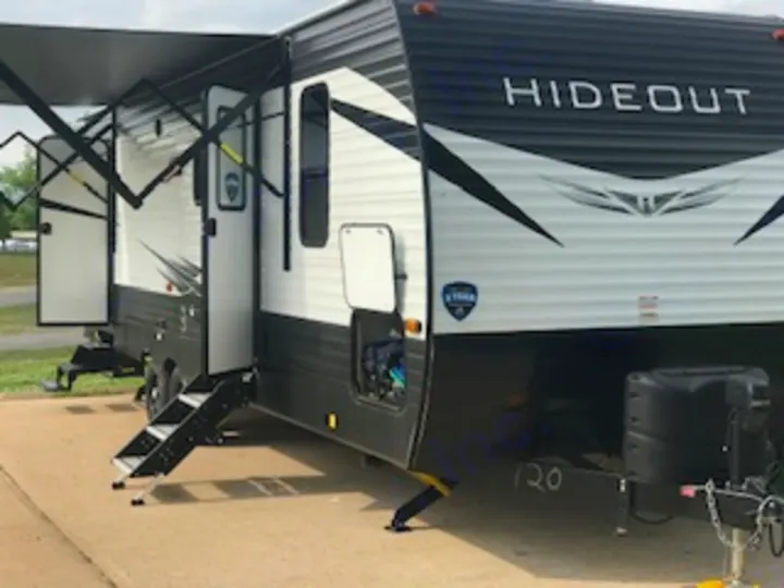 This black and white Hideout travel trailer RV rental, with its awning and steps extended, is ready for your camping trip.. Keystone Hideout 2021