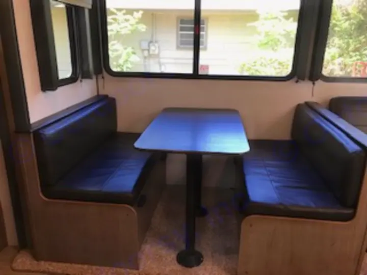 This RV rental features a clean dinette with comfy black benches, a sturdy table, and large windows for scenic views.. Keystone Hideout 2021