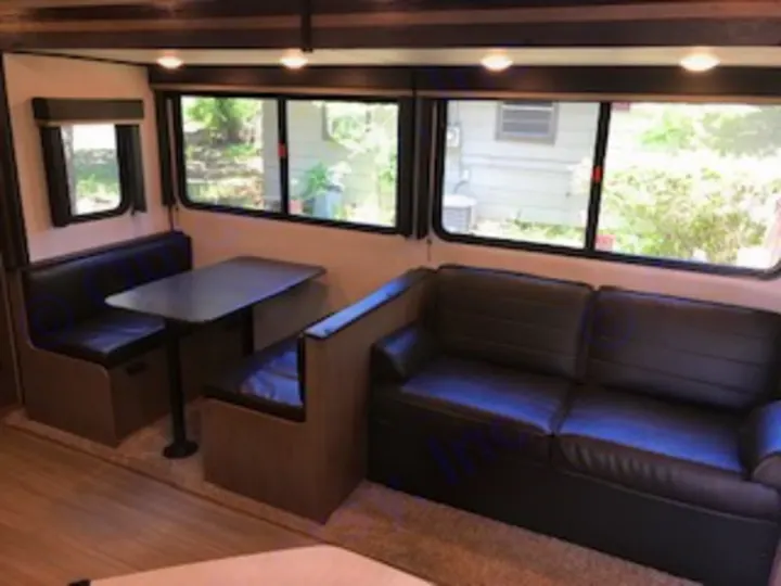 Explore this comfortable RV rental living area, featuring a dining booth, sofa, and scenic windows.. Keystone Hideout 2021