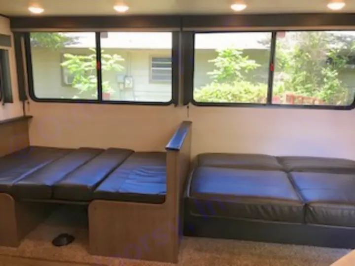 RV rental's comfortable interior: Featuring an extended bed, a sofa, and large windows with outdoor views.. Keystone Hideout 2021