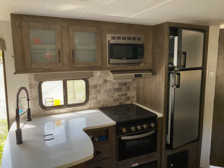 Bright RV rental kitchen featuring a sink, microwave, oven, fridge, and ample counter space for comfortable travel.. Forest River Evo 2020