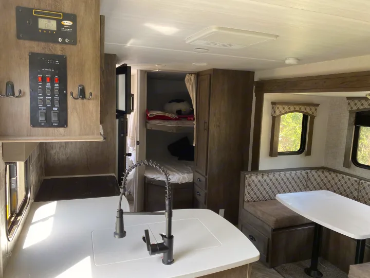 Step inside this rv rental's spacious interior, featuring a well-equipped kitchen, dining booth, and comfortable bunk beds.. Forest River Evo 2020