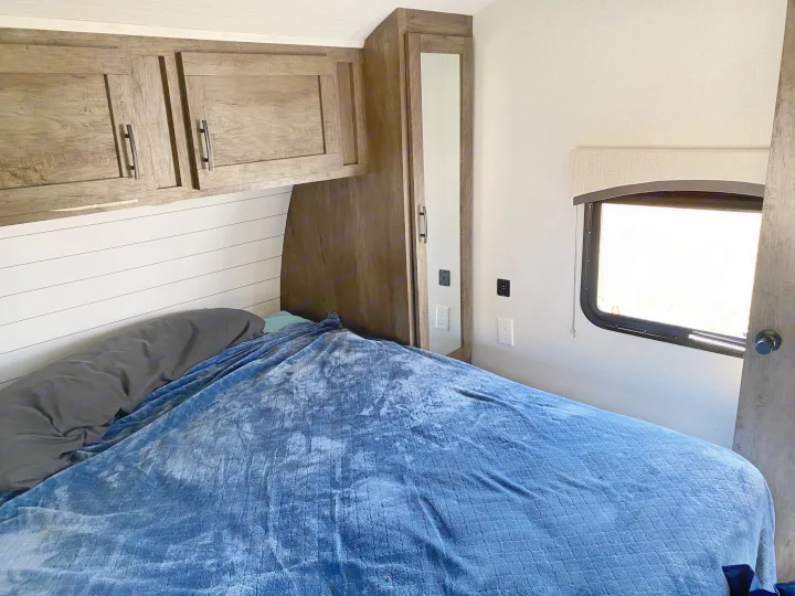 Cozy RV rental bedroom with a comfortable bed, overhead cabinets, and a mirrored wardrobe.. Forest River Evo 2020