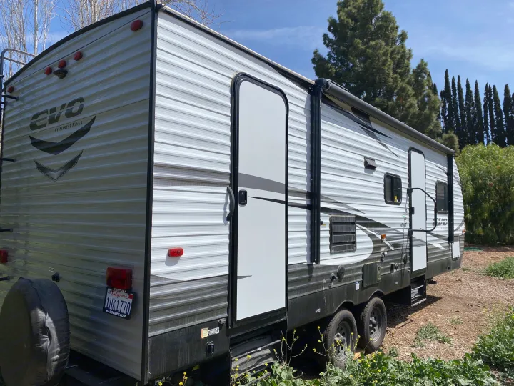 Gray & white Forest River EVO travel trailer RV rental, parked outdoors in a leafy setting.. Forest River Evo 2020