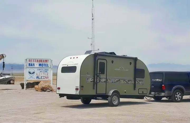 An RV rental travel trailer with an extended antenna, hitched to a pickup, is parked at the iconic Little A'Le'Inn alien motel.. Other Other 2018