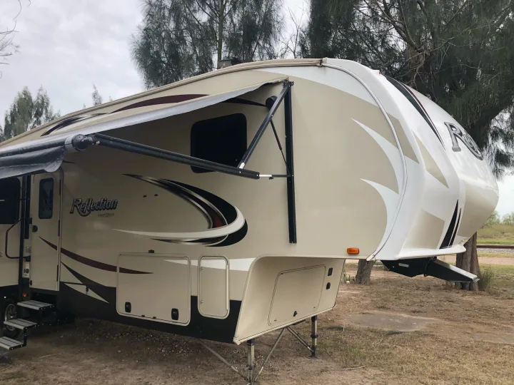 Spacious Reflection fifth-wheel RV rental parked with awning out at a campsite.. Grand Design Reflection 2017
