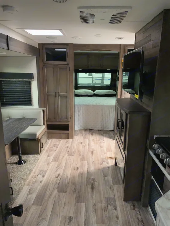 Inside this RV rental, discover a bright living space with wood-look floors leading to a dining booth, kitchen, and cozy private bedroom.. Venture Rv Sporttrek 2022