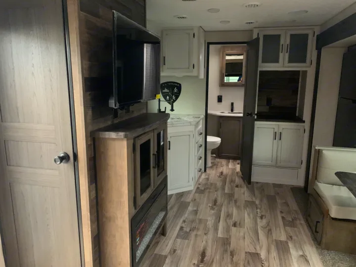 Inside this RV rental: modern living space with TV and fireplace, full bathroom, and comfortable dinette area.. Venture Rv Sporttrek 2022
