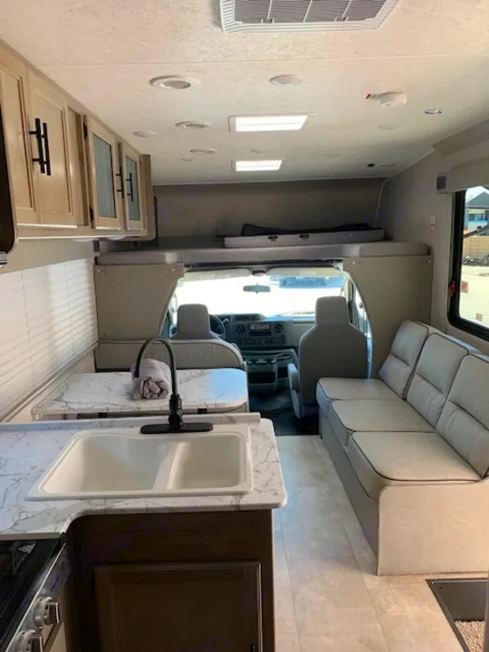 Step inside this RV rental: a cozy motorhome interior with a bright kitchen, comfy sofa, and front cockpit.. Coachmen Freelander 2021