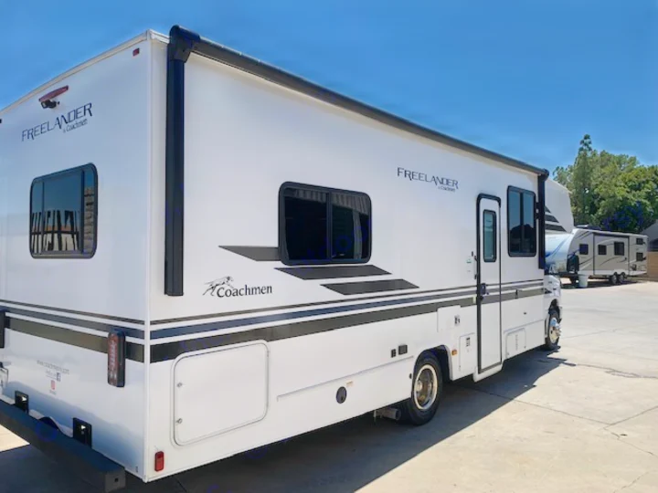 White Freelander Coachmen Class C RV rental, featuring sleek black accents, parked outdoors on a sunny day.. Coachmen Freelander 2021