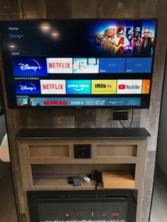 Modern RV rental living area featuring a large smart TV displaying streaming apps next to an entertainment cabinet.. Keystone Hideout 2021