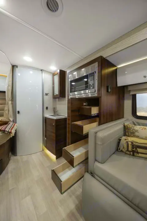 RV rental interior: modern kitchen with microwave, pull-out drawers, and comfortable sofa. Bright, functional space.. Winnebago View 2022