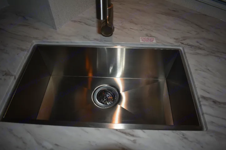 Shiny stainless steel kitchen sink and marbled countertop in an RV rental.. Keystone Passport 2021