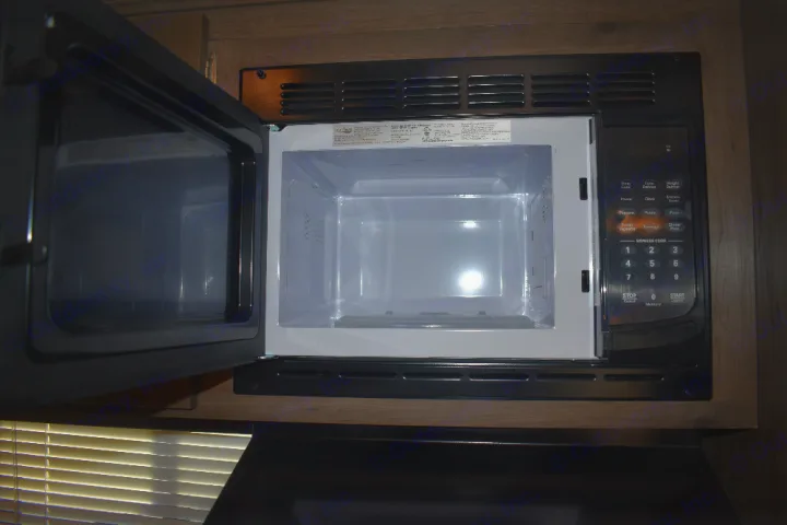 Essential kitchen appliance in your RV rental: a clean, open microwave oven with visible controls.. Keystone Passport 2021