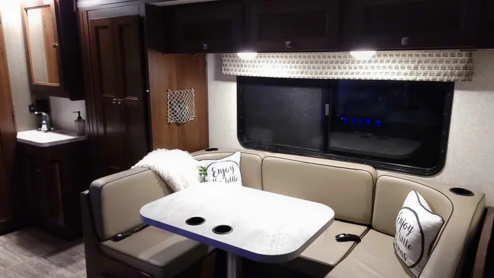 Cozy RV rental interior featuring a dinette with seating, a compact bathroom, and overhead storage for comfortable travel.. Forest River Sunseeker 2019