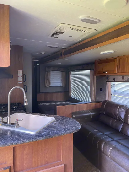 RV rental interior showcasing the kitchen with sink and counter, a dinette, and comfortable sofa seating.. Keystone Summerland 2017