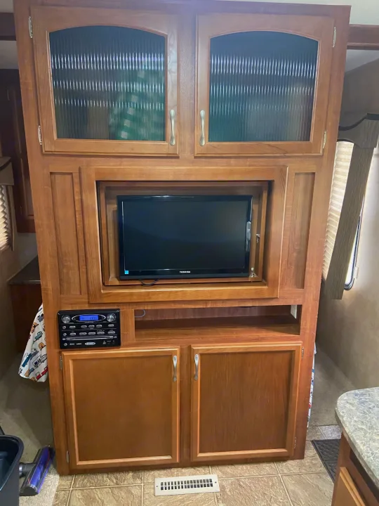 RV rental: warm wood entertainment center featuring a TV, stereo, and glass-paneled storage cabinets.. Jayco Camper Trailer- Eagle 2011
