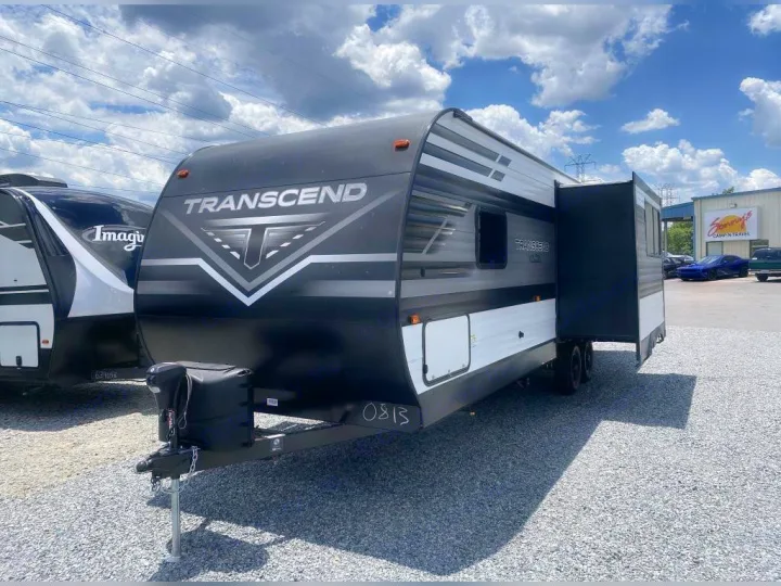 Black & white Transcend travel trailer with extended slide-out on a gravel lot, ready for RV rental.. Grand Design Transcend Xplor 2021