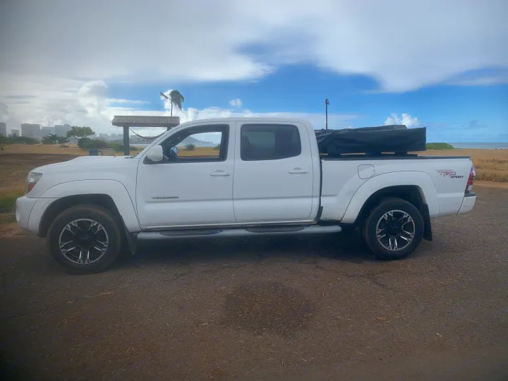 White Toyota Tacoma truck with covered rooftop tent, ideal RV rental for beach adventures in Hawaii.. Toyota Tacoma 2009