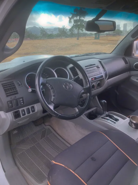 Interior of a Toyota vehicle, with steering wheel, dashboard, and wet windshield, great for an rv rental trip.. Toyota Tacoma 2009