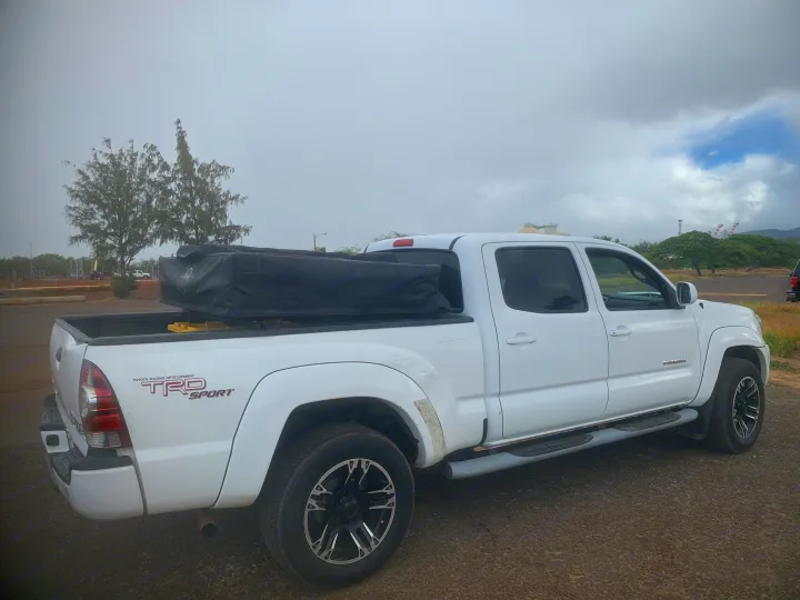 White Toyota Tacoma pickup with covered camping gear in bed. Explore versatile travel options from an RV rental service.. Toyota Tacoma 2009