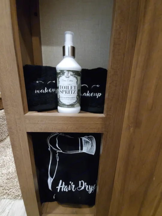 RV rental bathroom amenities: Toilet Spritz, makeup towels, and a hair dryer bag on a cozy wooden shelf.. Forest River Coachmen Chaparral Lite 2020