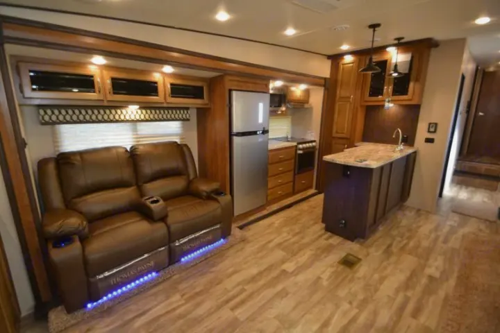 Spacious RV rental interior: kitchen, living area with recliner loveseat & wood cabinetry, offering modern comforts.. Forest River Coachmen Chaparral Lite 2020