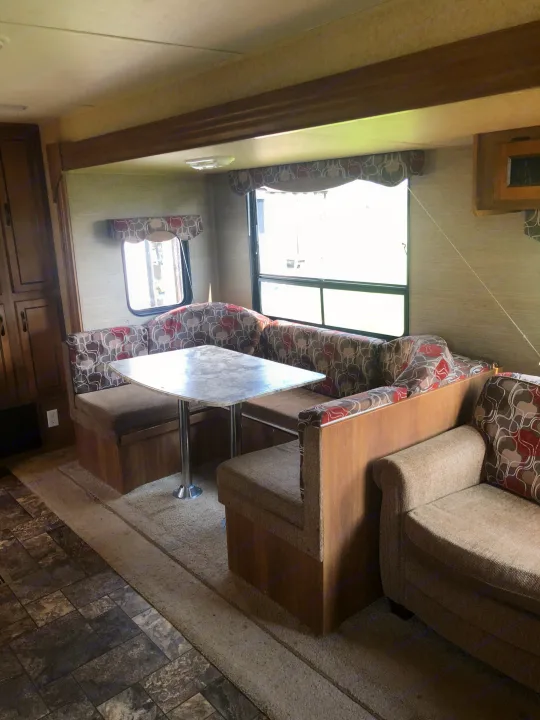 Spacious RV rental interior featuring a U-shaped dinette with patterned cushions, comfy lounge seating, and bright windows.. Forest River Coachmen Catalina 2016