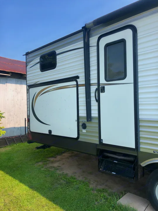 RV rental: Side view of a white and green travel trailer featuring a door, window, and rolled-up awning, on grass.. Forest River Coachmen Catalina 2016