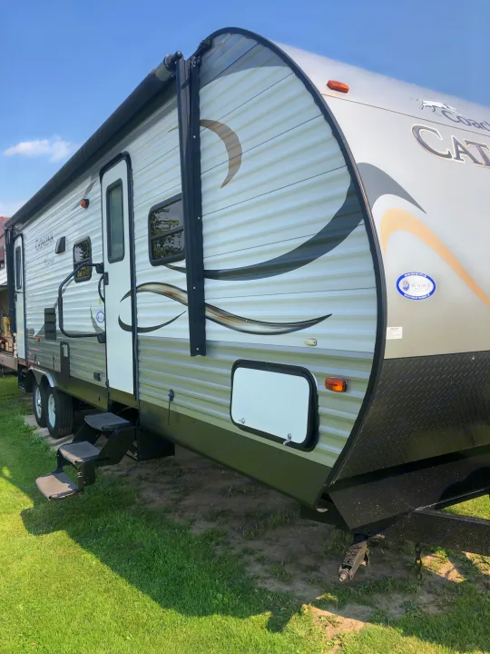 This Catalina travel trailer, an excellent option for rv rental, is seen parked outdoors with its steps down and awning rolled up.. Forest River Coachmen Catalina 2016