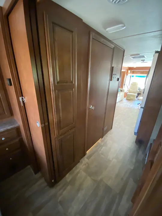 Inside an RV rental, a well-appointed hallway with dark wood cabinetry leads to the cockpit area, featuring comfortable seating.. Forest River Georgetown 2015