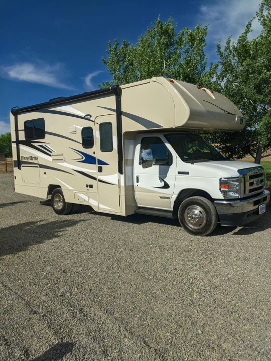 Class C RV rental: A beige Winnebago Minnie Winnie motorhome parked on gravel under a clear sky.. Winnebago Minnie Winnie 2022