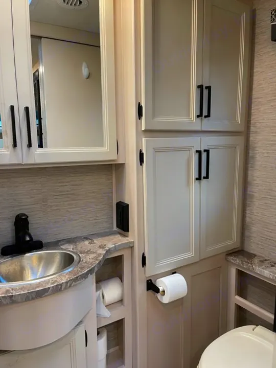 RV rental interior: light cabinets, compact kitchen sink, paper towels, and toilet. Efficient amenities for travel.. Thor Gemini 2021