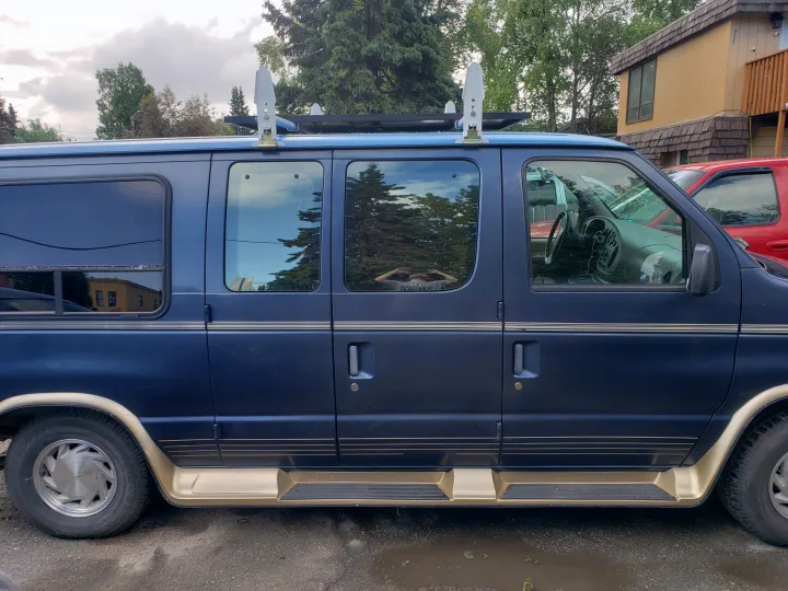 A dark blue conversion van with gold trim and roof-mounted solar panels, ideal for an RV rental adventure.. Ford Econoline Club Wagon 1998