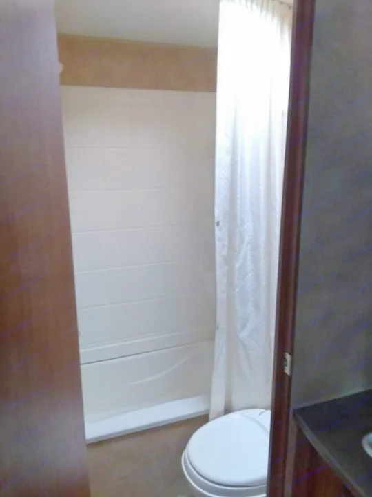 Inside an RV rental: a compact bathroom featuring a white tiled shower/tub, toilet, and white shower curtain. Clean and functional.. Jayco Jay Flight Swift 2012