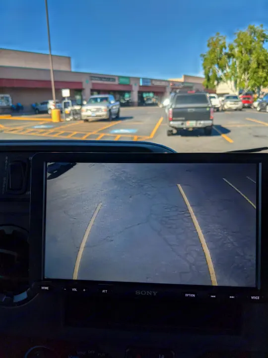 Inside an RV rental, the rearview camera aids in parking in a sunny lot, showing clear guidelines on the Sony display.. Winnebago Minnie Winnie 2022