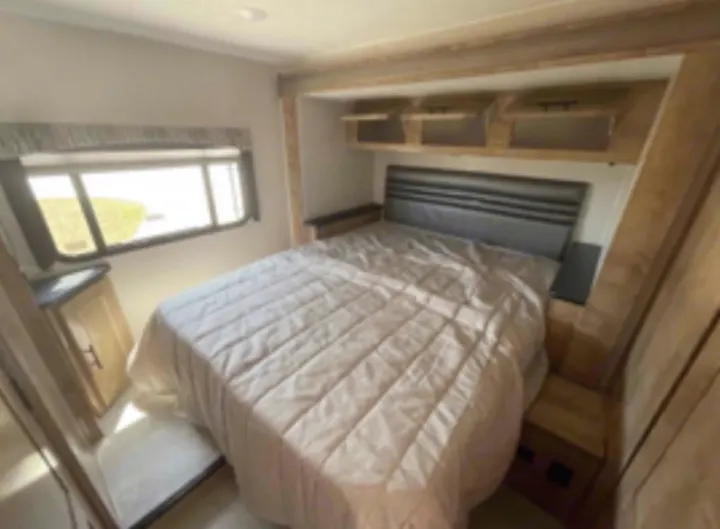Explore this cozy RV rental bedroom. Features a comfortable bed, window views, and ample overhead storage for your adventure.. Coachmen Leprechaun 2021