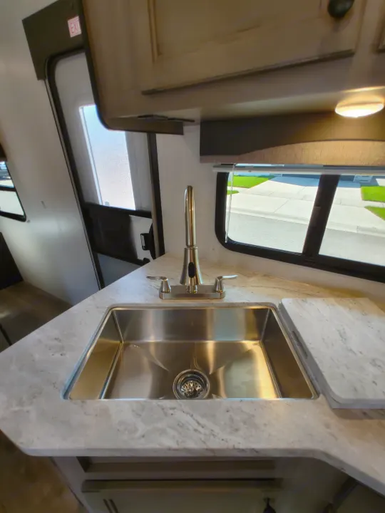 RV rental kitchen featuring a stainless steel sink, modern faucet, and light stone countertops.. Starcraft Travel Trailer 2021
