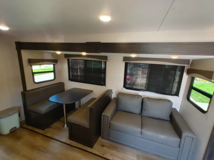 Cozy RV rental interior with a comfy sofa, dinette, and bright windows, offering a comfortable living space for travel.. Starcraft Travel Trailer 2021