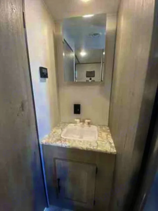 Compact RV rental bathroom vanity featuring a sink, mirror reflecting the interior, and lower storage cabinet.. Keystone Springdale 2021