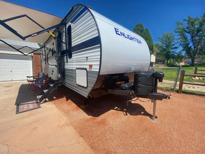 Spacious 'Enlighten' travel trailer RV rental parked with awning extended, two chairs set up. Ready for your adventure!. Gulf Stream Other 2021