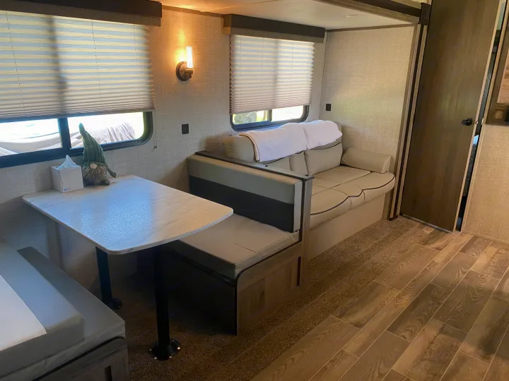 Bright rv rental interior, featuring a dinette with table & bench, plus a comfortable sofa and windows with blinds.. Gulf Stream Other 2021