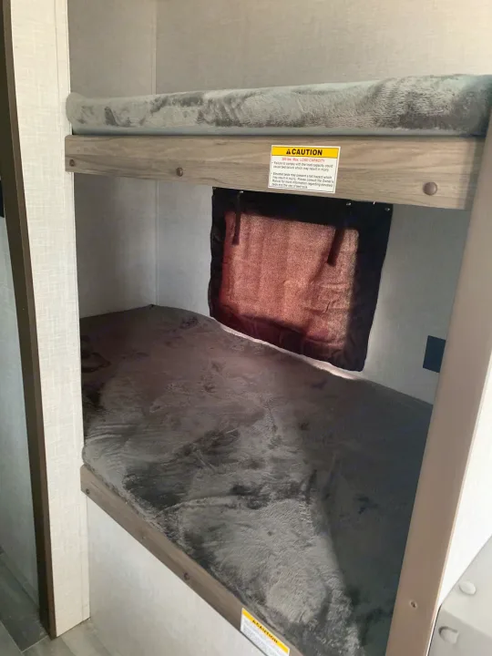 RV rental featuring stacked bunk beds with soft blankets and a vital weight capacity warning sticker.. Crossroads Zinger 2021