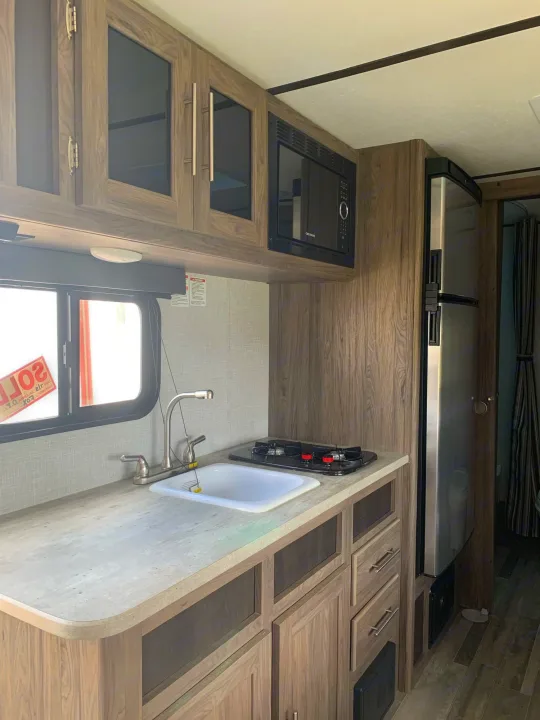 Well-equipped RV rental kitchen: full counter, sink, stove, microwave, and large fridge.. Crossroads Zinger 2021